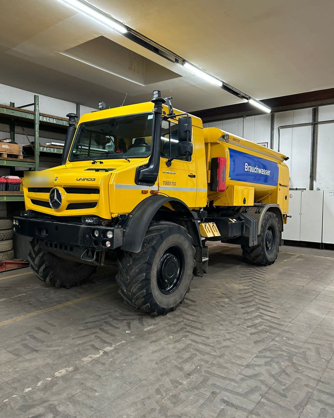 Gelber Mercedes-Benz Unimog mit Tankaufbau in einer Werkstatthalle